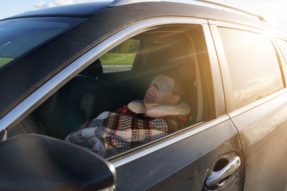 A,Tired,Driver,Sleeps,In,The,Car,During,The,Day, autóban alszik elektromos autó