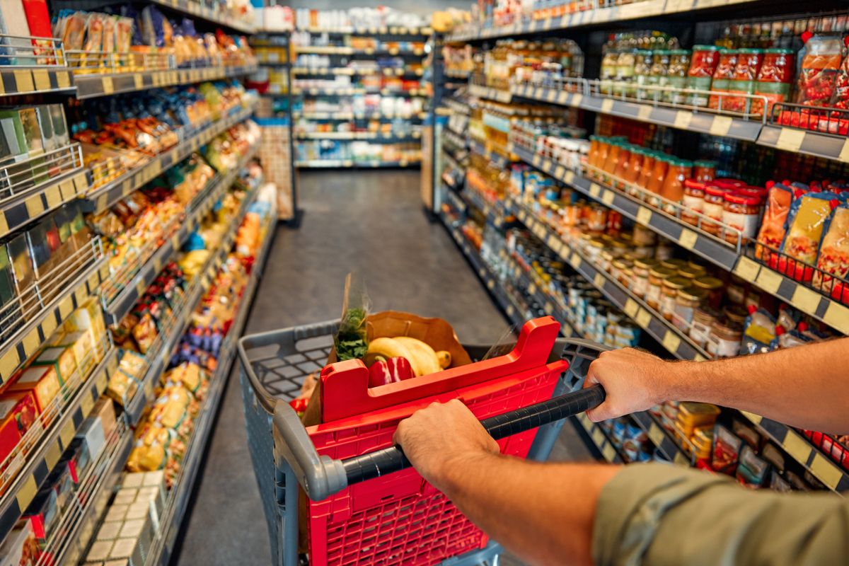A,Man,With,A,Cart,Walks,Between,Store,Shelves,And szilveszteri nyitvatartás bolt, Húsvéti nyitva tartás